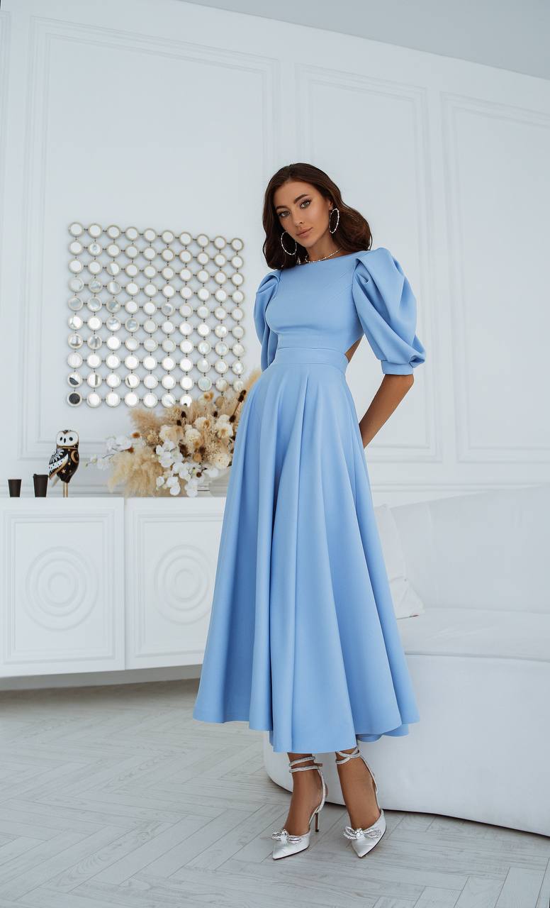 Woman wearing a light blue dress with puffed sleeves in a room with decorative elements.
