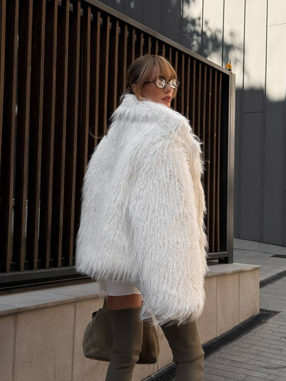 Person wearing a white fluffy coat walking outdoors.