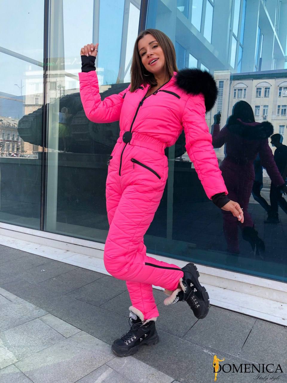 Person wearing a bright pink snowsuit with black accents in an urban setting.