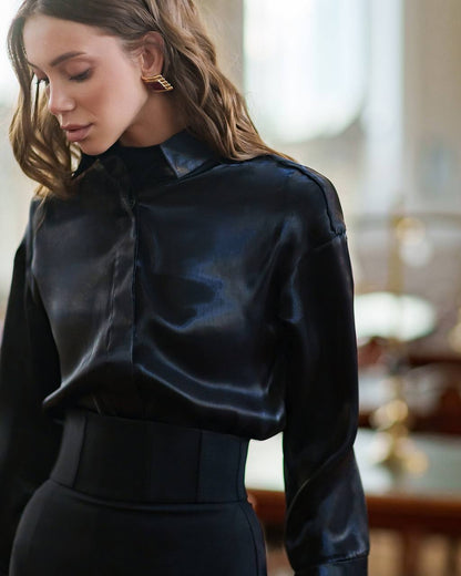 Woman wearing a black satin blouse in an indoor setting
