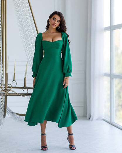Woman wearing a green dress in a bright room with large windows.