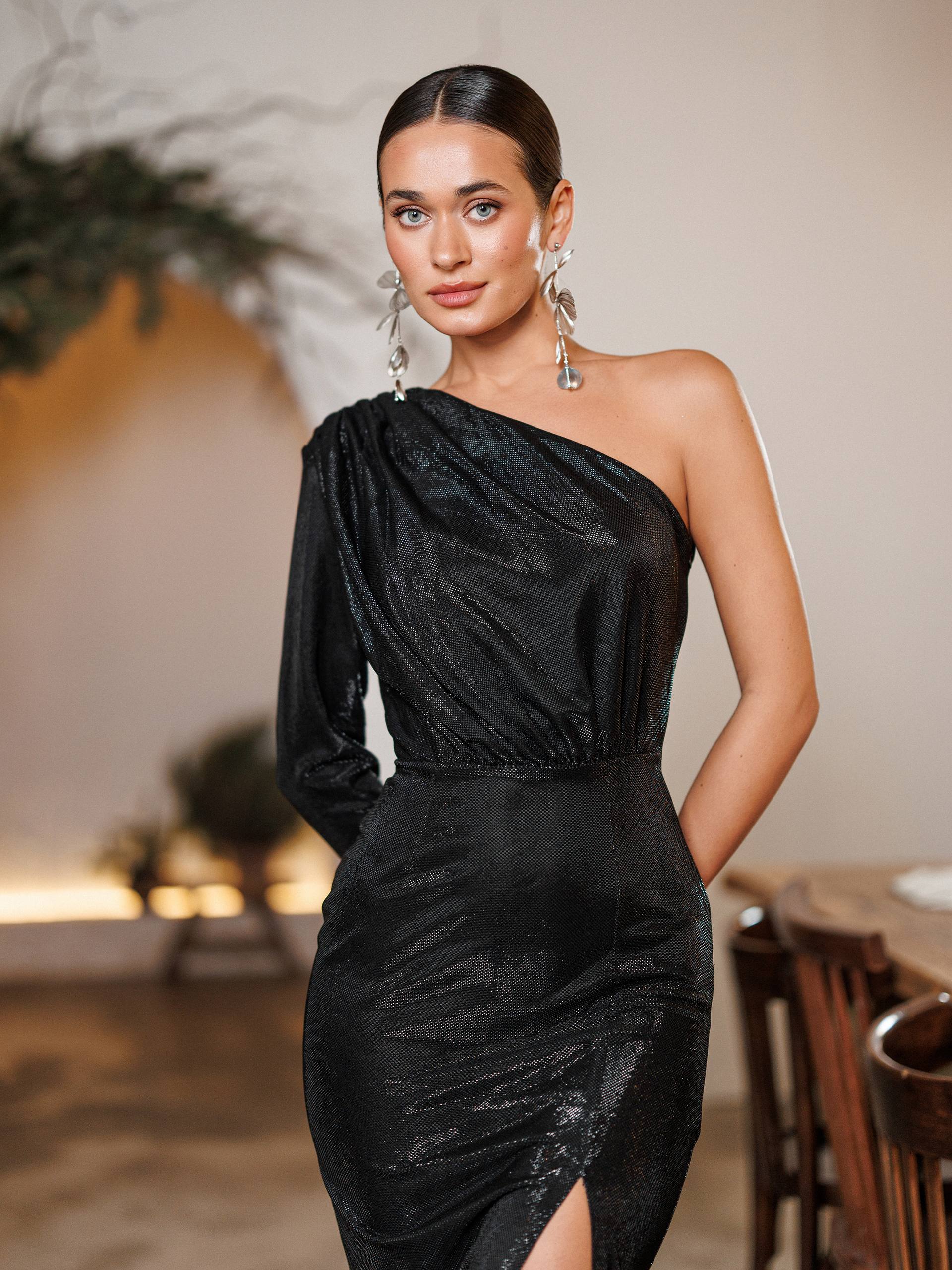 Woman wearing a black one-shoulder dress in an indoor setting