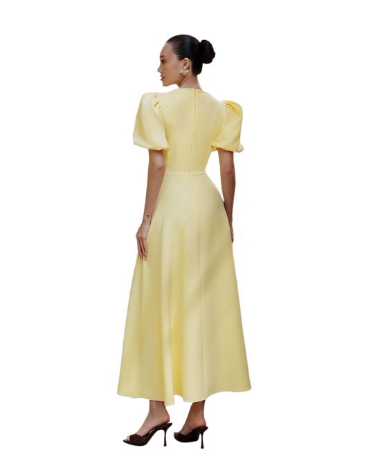 Woman wearing a yellow dress with puff sleeves on a white background