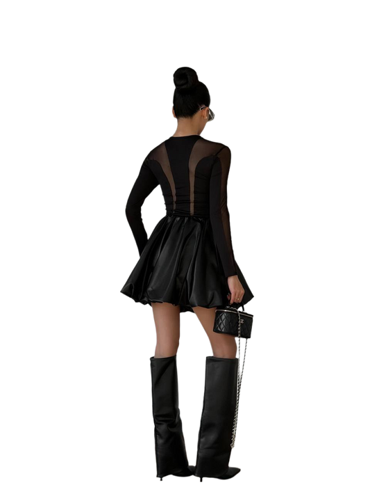 Person wearing a black dress with sheer panels and black knee-high boots on a white background
