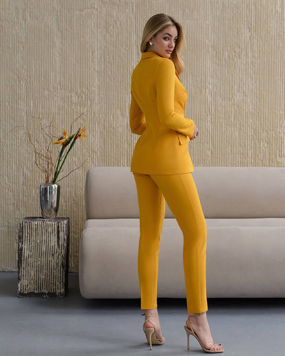 Woman in a yellow suit standing in a room with a couch and decorative plant.