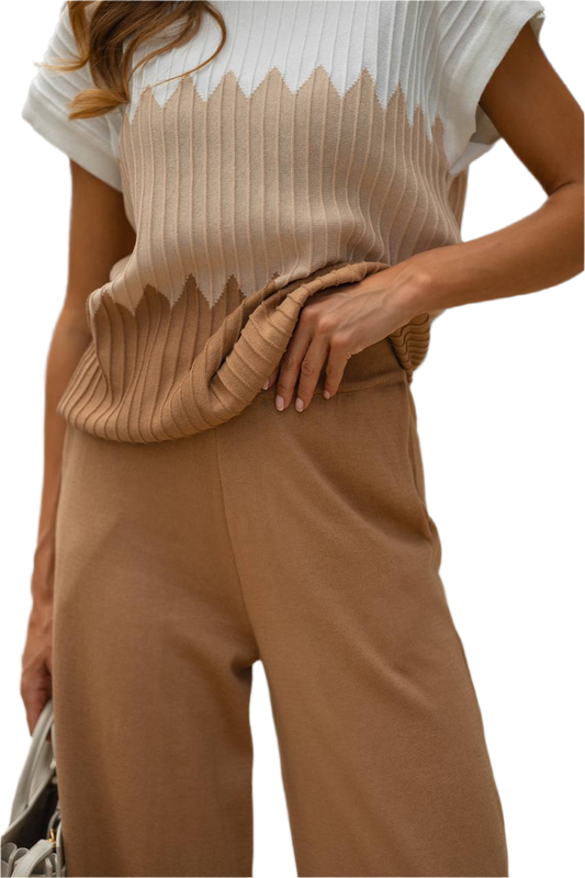 Person wearing a beige ribbed top and brown pants on a white background