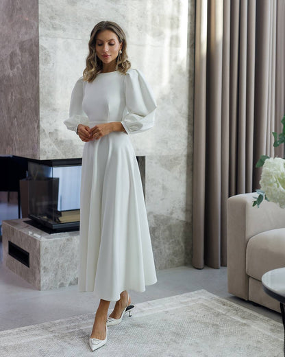 Woman in a white dress standing in a modern living room.