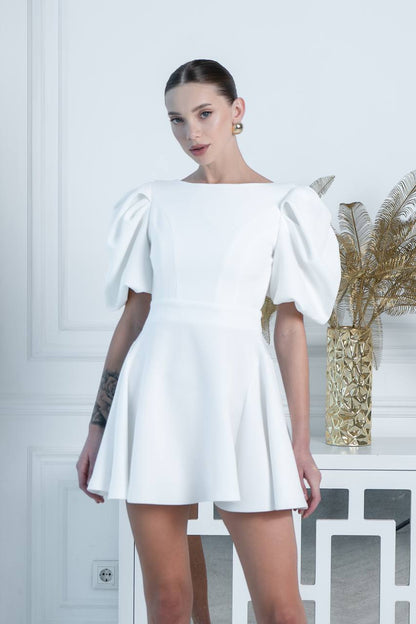 Woman wearing a white dress with puffed sleeves against a light background