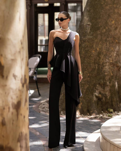 Woman wearing a black strapless top and wide-leg pants in an outdoor setting.