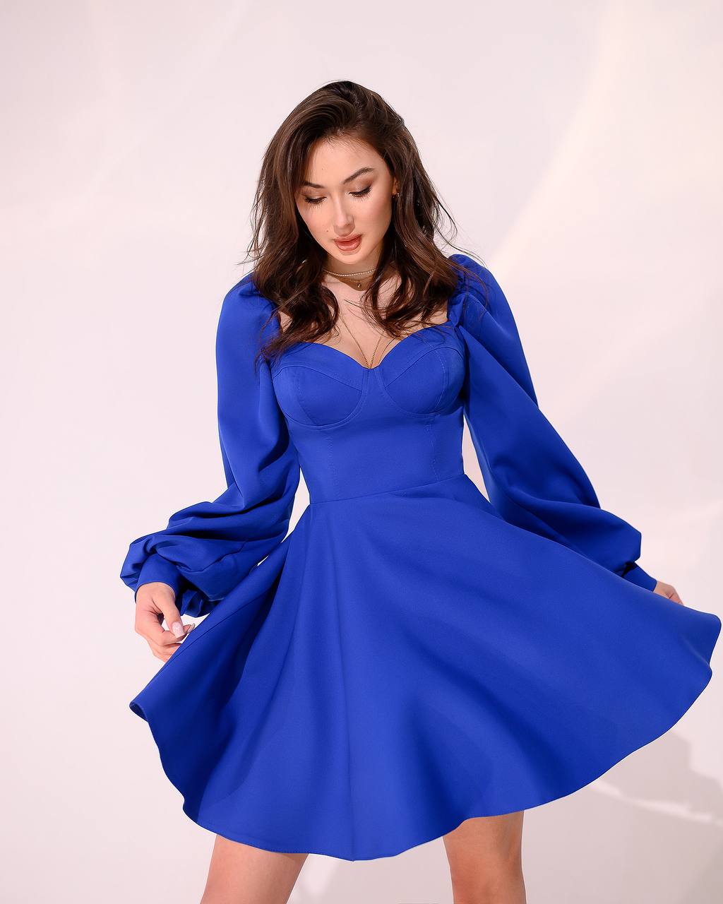 Woman wearing a blue dress with long sleeves on a white background