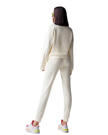Person wearing a white tracksuit with colorful sneakers on a white background