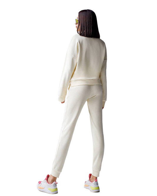 Person wearing a white tracksuit with colorful sneakers on a white background