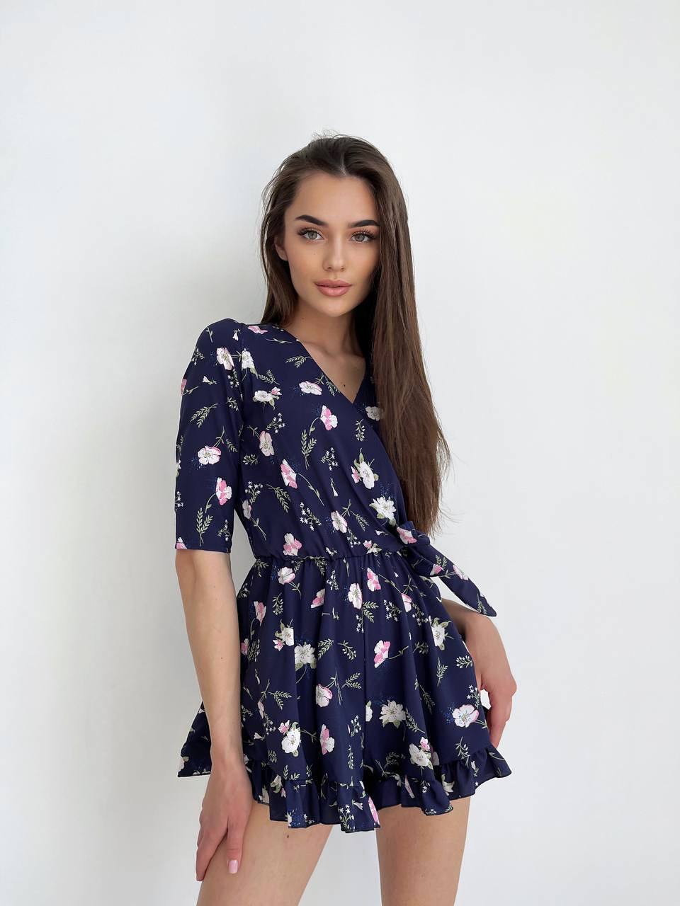 Woman wearing a navy floral dress against a white background