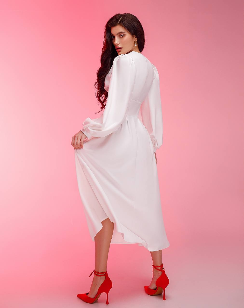 Woman in a white dress with red shoes on a pink background
