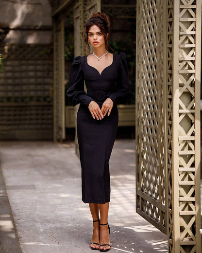 Woman in a black dress standing in front of a textured wall.