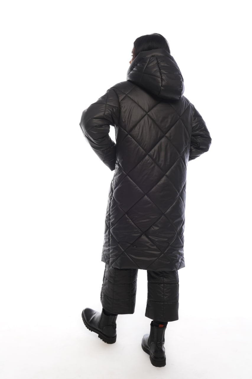 Person wearing a black quilted coat on a white background
