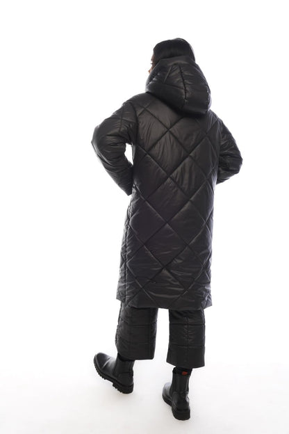 Person wearing a black quilted coat on a white background