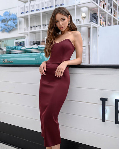 Woman in a burgundy strapless dress standing in a modern interior setting.
