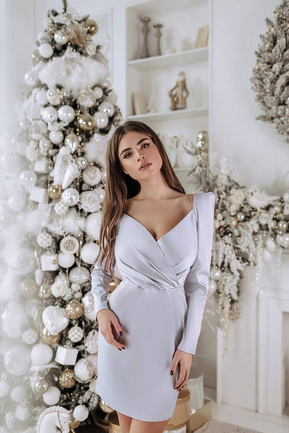 Woman in a white dress standing in a decorated room with Christmas decorations.