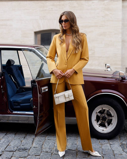Woman in a mustard yellow suit standing next to a vintage car