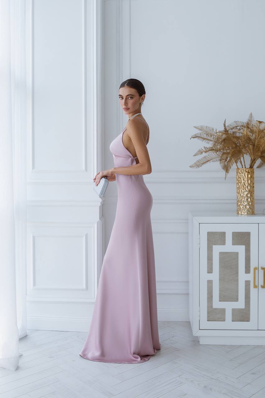 Woman in a pink evening gown standing in a stylish room with decorative elements.