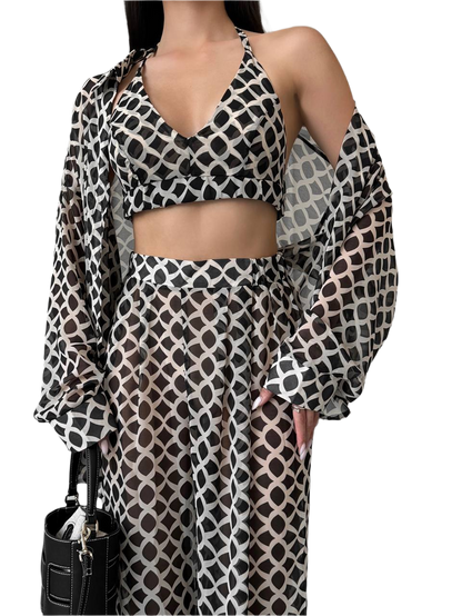 Woman wearing a patterned outfit with a black handbag on a white background