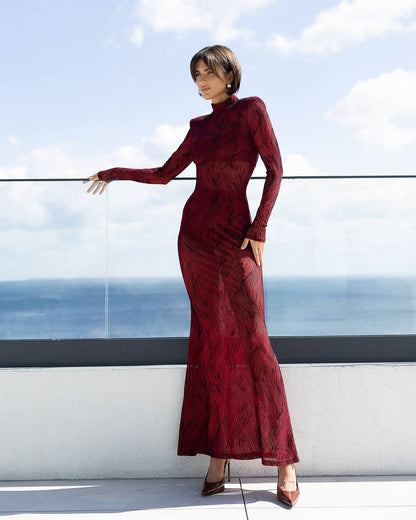 Woman in a red dress standing on a rooftop with ocean view