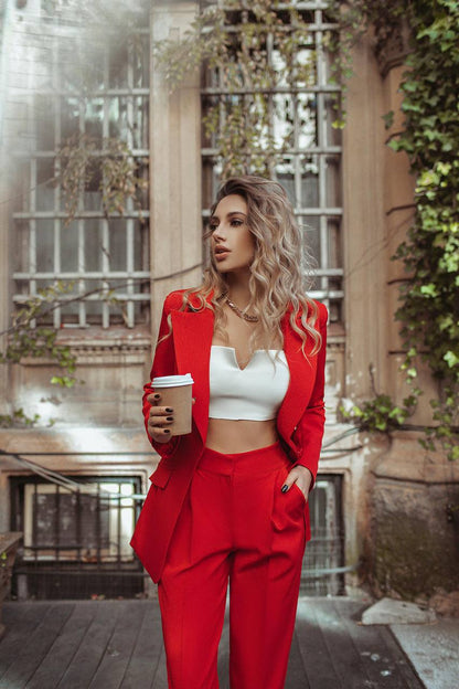 Woman in a red suit holding a coffee cup in an urban setting
