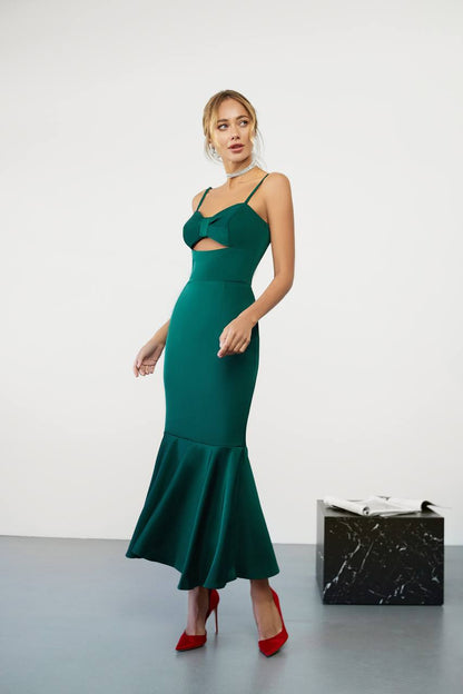 Woman wearing a green evening gown with a cutout design, standing against a white background.