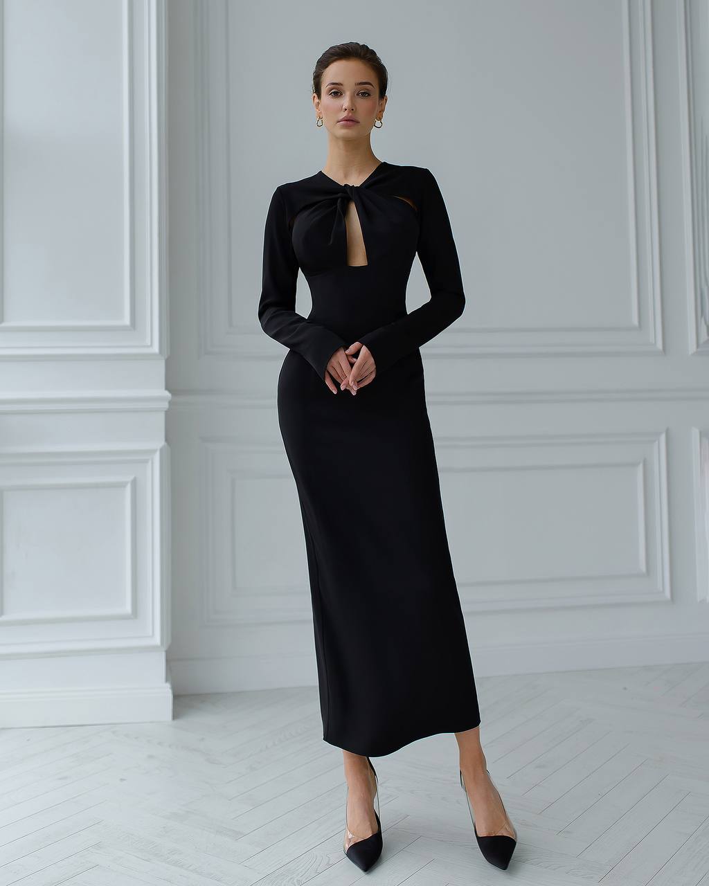 Woman wearing a black dress with a bow detail in a minimalistic setting