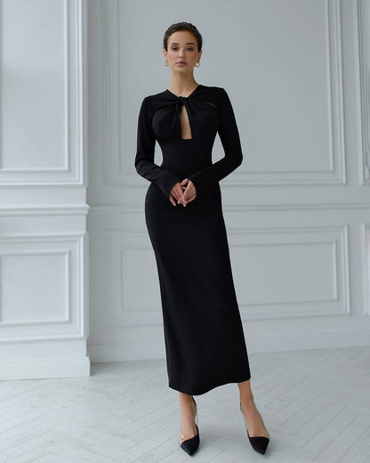 Woman wearing a black dress with a bow detail in a minimalistic setting