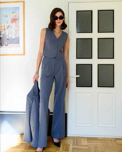 Woman in a blue jumpsuit standing in a room with a white door and framed picture on the wall.