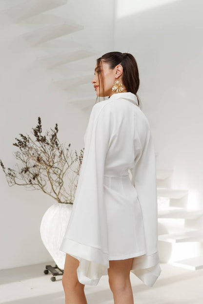 Woman wearing a white shirt in a minimalistic room with a plant.