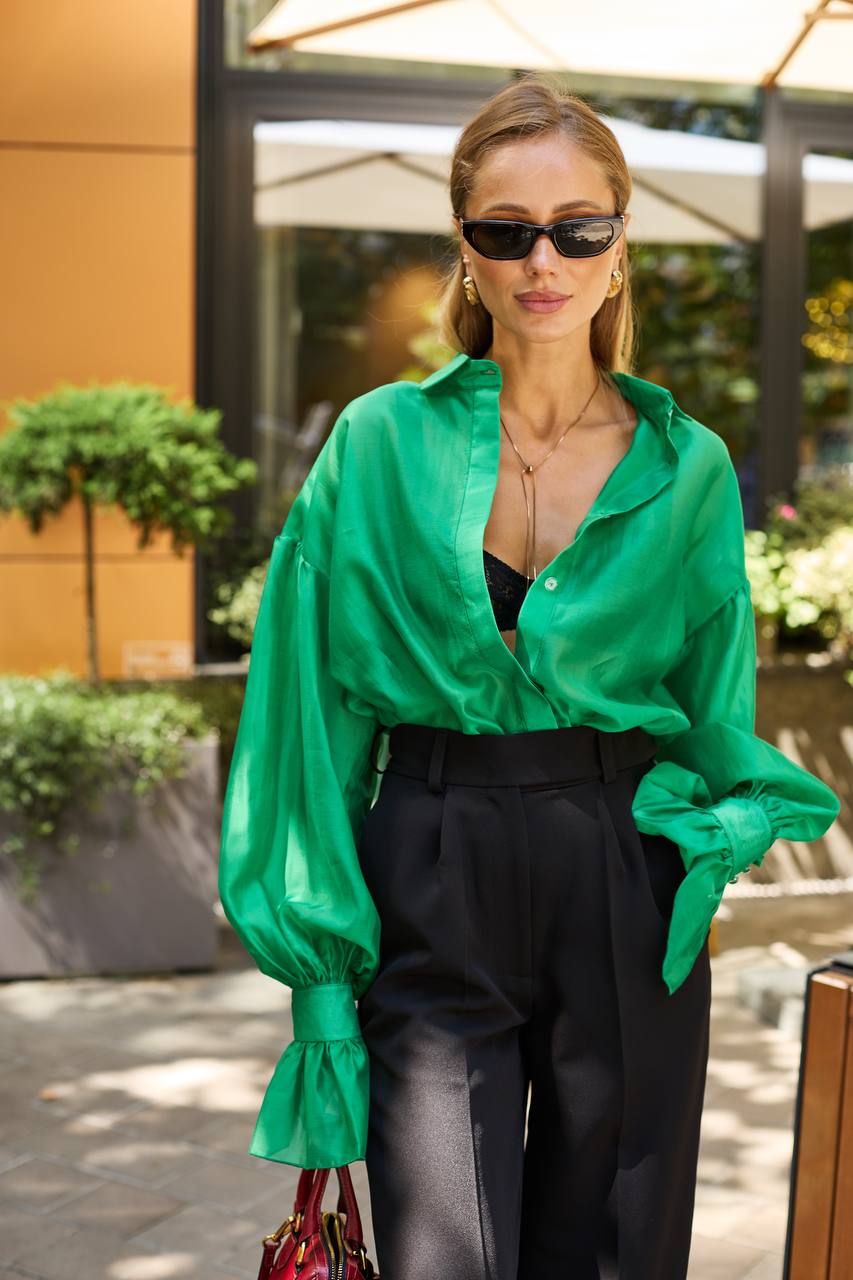Woman wearing a green blouse and black pants outdoors.