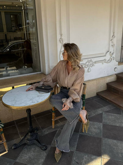 Woman sitting at a small round table outside a building with decorative elements.