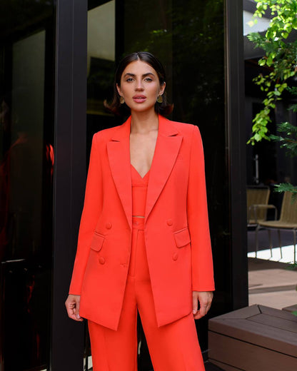 Woman wearing a bright orange suit standing outdoors.