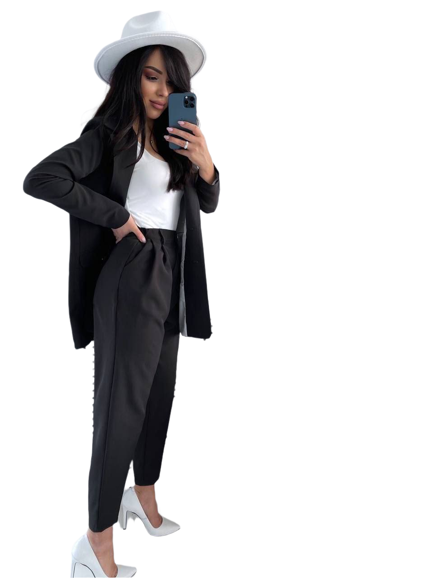 Woman in a black outfit with a white hat taking a selfie on a white background