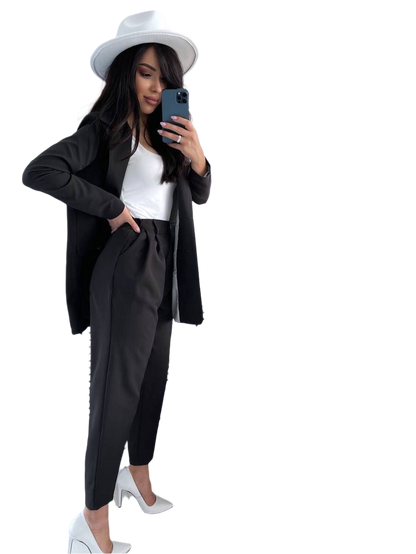 Woman in a black outfit with a white hat taking a selfie on a white background