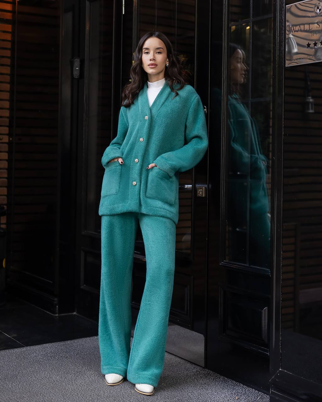 Woman in a teal outfit standing in front of a glass door.