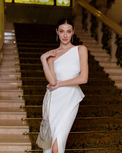 Woman in a white one-shoulder dress standing on a staircase