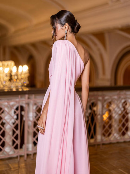 Woman in a pink one-shoulder dress standing in an elegant indoor setting.