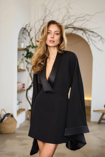 Woman wearing a black dress with a deep neckline in an indoor setting.
