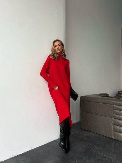Person wearing a red dress and black boots in a minimalistic room.