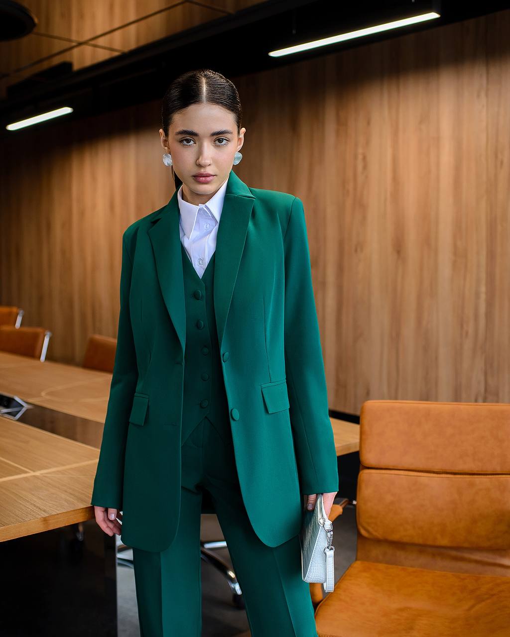 Woman in a green suit standing in a modern office setting