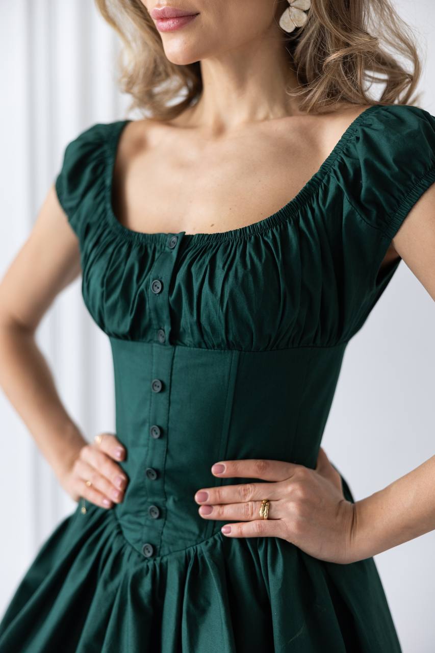 Green dress with a close-up of the neckline and buttons on a white background