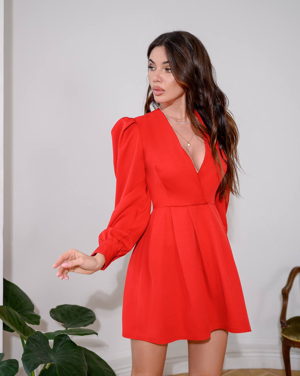 Woman wearing a red dress with long sleeves against a white background