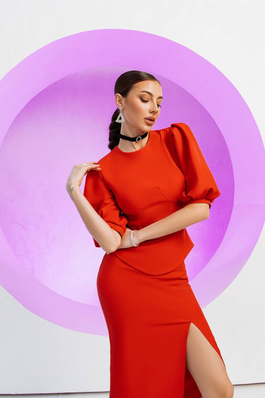 Woman wearing a red dress with puffed sleeves against a white background