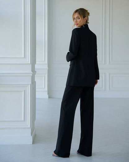 Woman wearing a black suit standing in a white room