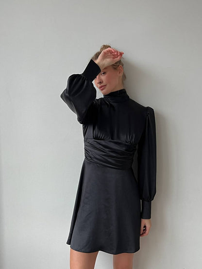 Person wearing a black dress against a plain background