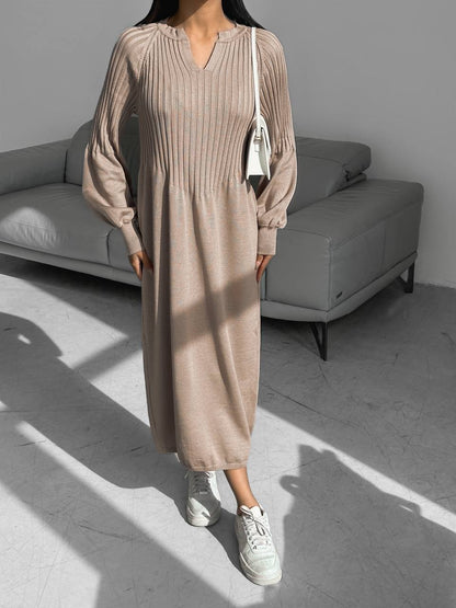 Person wearing a beige ribbed dress with white sneakers in a minimalistic room.